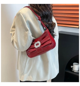 Detail of red patent leather shoulder bag with pleated texture and rhinestone buckle