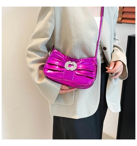 Detail of fuchsia metallic pleated crossbody bag with a sparkling crystal buckle ornament