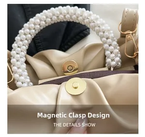 Detail of magnetic clasp closure and pearl handle on pleated beige crossbody bag