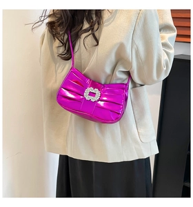 Close-up of pink metallic pleated shoulder bag with rhinestone buckle on model outfit