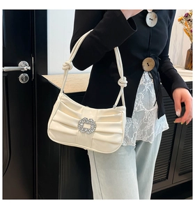 Detail of elegant pleated shoulder bag featuring a large crystal-encrusted round buckle