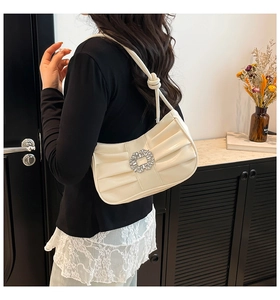 Detail showing the square rhinestone buckle and elegant pleated side on the off-white bag