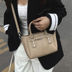 Khaki leather tote bag with silver hardware worn by a model in a minimalist style