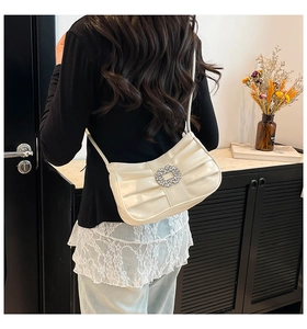 Chic cream pleated shoulder bag with sparkling rhinestone buckle shown in a lifestyle setting