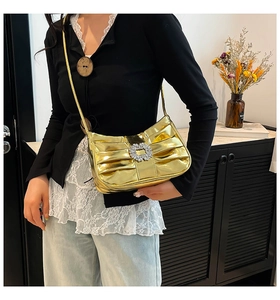 Detail of gold metallic pleated shoulder bag with sparkling crystal buckle on side view
