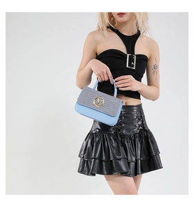 Détail du sac à main bicolore avec rayures grises et cuir bleu porté par un mannequin