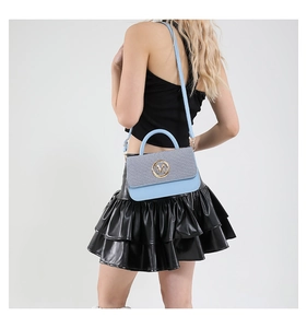 Détail d'un sac à main bicolore bleu et gris avec logo M métallique et bandoulière en cuir
