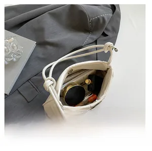 Macro detail of spacious interior in cream pleated PU leather bag showing daily essentials