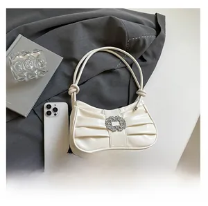 Detailed macro view of pleated cream leather bag with a luxury crystal buckle and tied handle