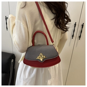 Detail einer rot-grauen Handtasche mit goldener Perlenschnalle an einem Model