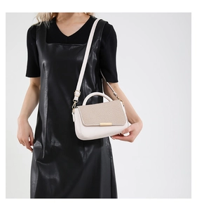 Dettaglio di borsa chic bicolore beige in ecopelle con patta intrecciata color kaki