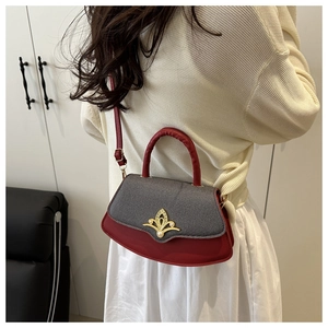 Detailsicht der rot-grauen Patchwork-Handtasche mit goldener Blumenschließe und weißer Perle