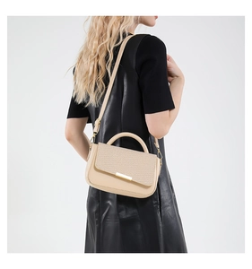 Dettaglio borsa beige con patta a trama intrecciata e chiusura in metallo dorato