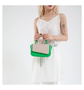 Dettaglio della borsa verde con patta beige testurizzata e fibbia in metallo oro