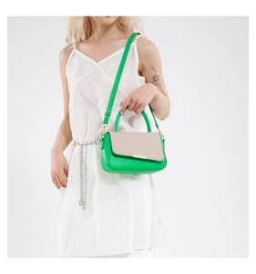Dettaglio borsa a mano in pelle verde e paglia intrecciata con chiusura dorata e tracolla