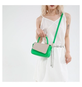 Dettaglio borsa in pelle verde con patta in paglia beige e catena in argento lucido