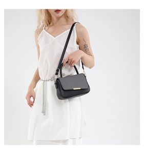 Dettaglio di un'elegante borsa in pelle nera con chiusura dorata portata da una modella