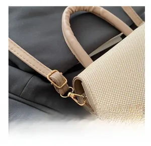 Detailaufnahme der goldenen Metallschnalle und Webtur auf der beigen Handtasche