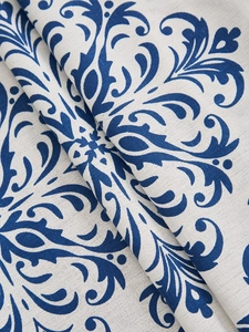 Close-up of blue damask pattern on white tablecloth showing textile texture and fabric drape