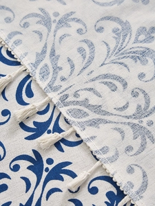 Detail of blue floral cotton linen tablecloth with elegant woven tassel trim edges