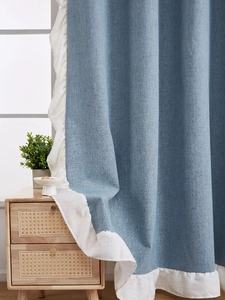 Détail d'un rideau bleu aspect lin avec bordure à volants blancs et tissu occultant