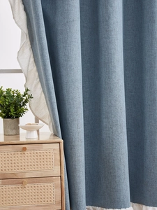 Détail de rideau en lin bleu avec bords à volants blanc crème et tissu épais texturé