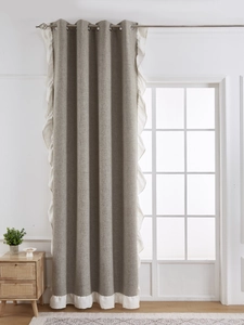 Detail of grey linen blackout curtain featuring white ruffle edge and silver grommet top