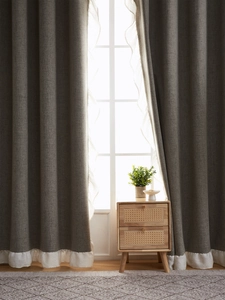 Detail of dark grey linen curtains with white ruffled edges in a modern living room
