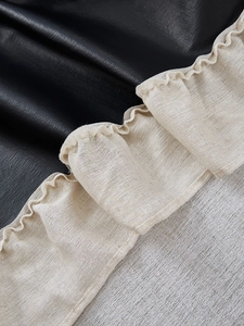 Detailed view of ruffle stitching between black leather and beige linen curtain fabric
