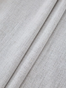 Close-up of thick light gray linen curtain fabric showing textured weave and soft drape