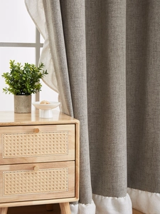 Detail of grey linen blackout curtain featuring elegant white cotton ruffle hem trim
