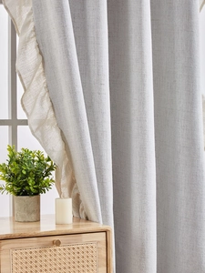 Detailed view of light grey linen curtain with elegant beige ruffled edge decoration