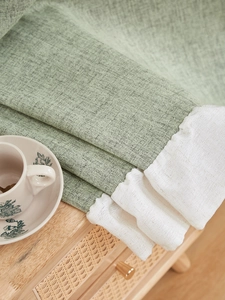 Dettaglio di spessa tenda in lino verde chiaro con bordo bianco decorativo a volant