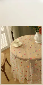 Close-up of colorful floral embroidery on white lace tablecloth with vintage mesh texture