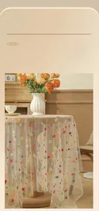 Detail of beige lace tablecloth featuring delicate floral embroidery and smooth drape
