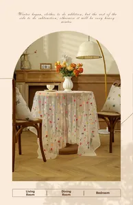 Detail of white mesh lace tablecloth with colorful floral embroidery in a warm rustic setting