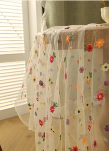 Detailed close-up of pastoral lace tablecloth featuring colorful floral embroidery
