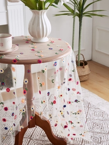Detail of white mesh tablecloth with delicate multi-color floral embroidery for home decor