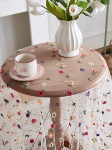 Detail of colorful floral embroidery on sheer lace tablecloth for elegant tea settings