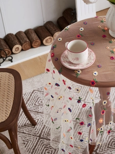 Detail of colorful floral embroidery on white transparent lace mesh tablecloth