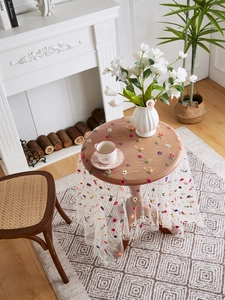 Detail showing white sheer lace tablecloth with delicate floral embroidery on a table