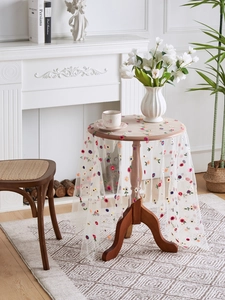Detail view of colorful floral embroidery on white lace tulle tablecloth for home decor