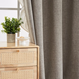 Thick grey linen blackout curtain with metal rings hanging in a cozy living room scene
