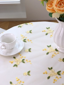 Close-up of white lace mesh tablecloth featuring delicate yellow floral embroidery