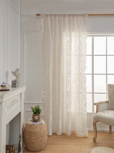 Dettaglio di ricamo floreale vintage e bordo con volant su tende beige velate