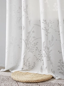 Détail du rideau blanc semi-transparent avec broderie de branches botaniques grises