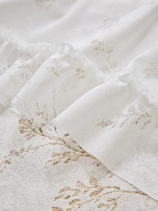 Détail de rideau en dentelle blanche avec motifs floraux ajourés et bords à volants
