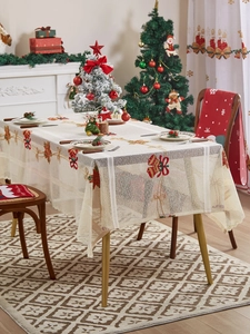 Detail van Kerst kanten tafelkleed met geborduurde kerstbel en rode strik decoraties