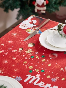 Detailed close-up of a festive red Christmas tablecloth with Santa Claus and snowflake prints