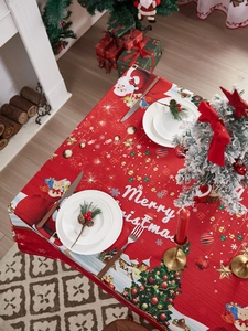 Festive red tablecloth detail with Merry Christmas print and Santa Claus holiday patterns